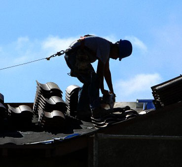 A construction worker cuts tiles as he installs a roof on a home in a new subdivision being built in San Marcos, California