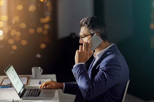 Shot of a businessman using his phone while woking late in the office