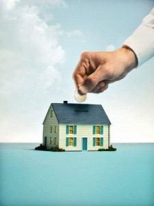 Hand putting coins into house piggy bank