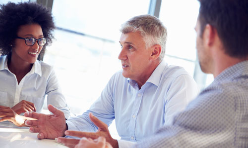 Three people are seated at a table talking