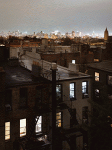 Older buildings with illuminated city in distance