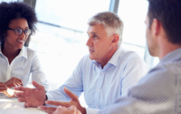 Three people are seated and talking